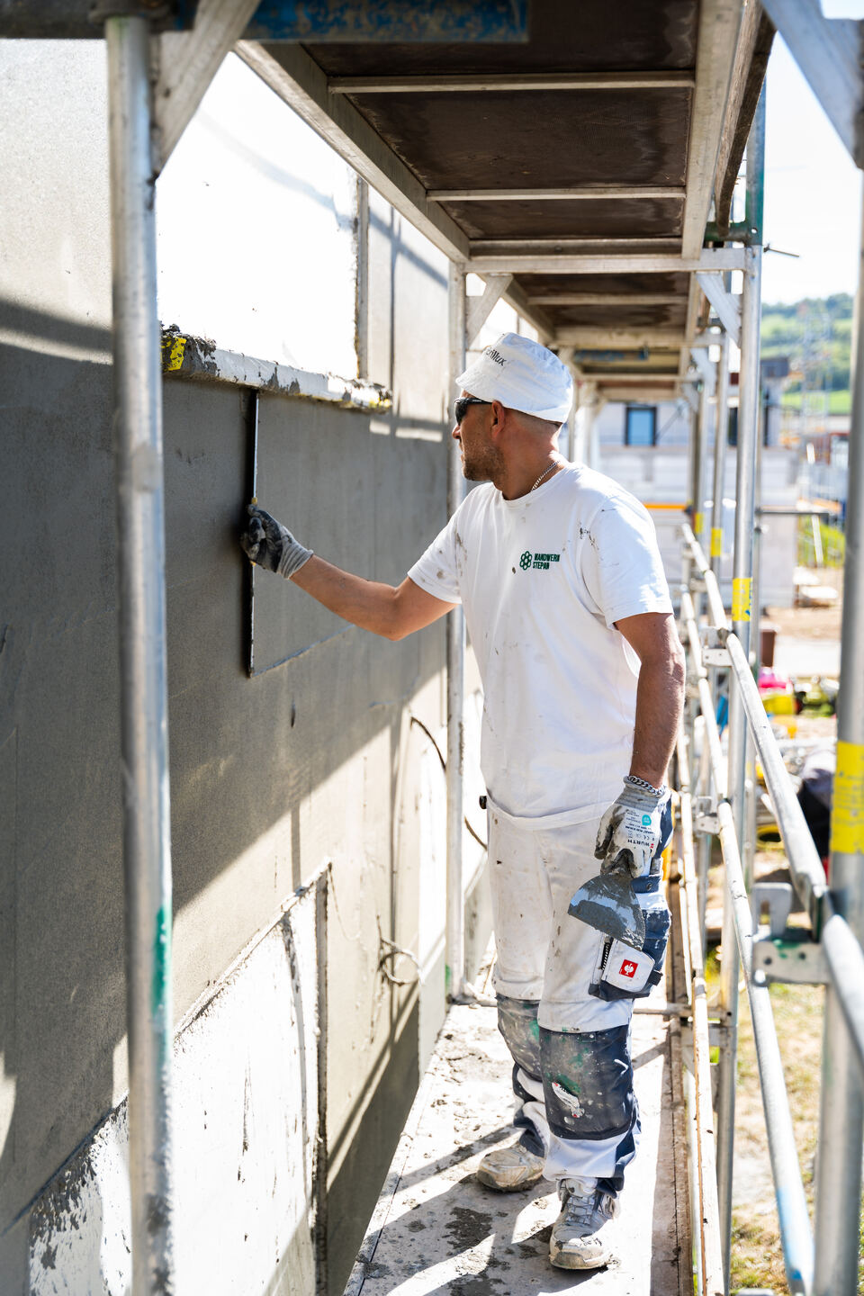 Mitarbeiter trägt Außenputz auf eine Fassade auf