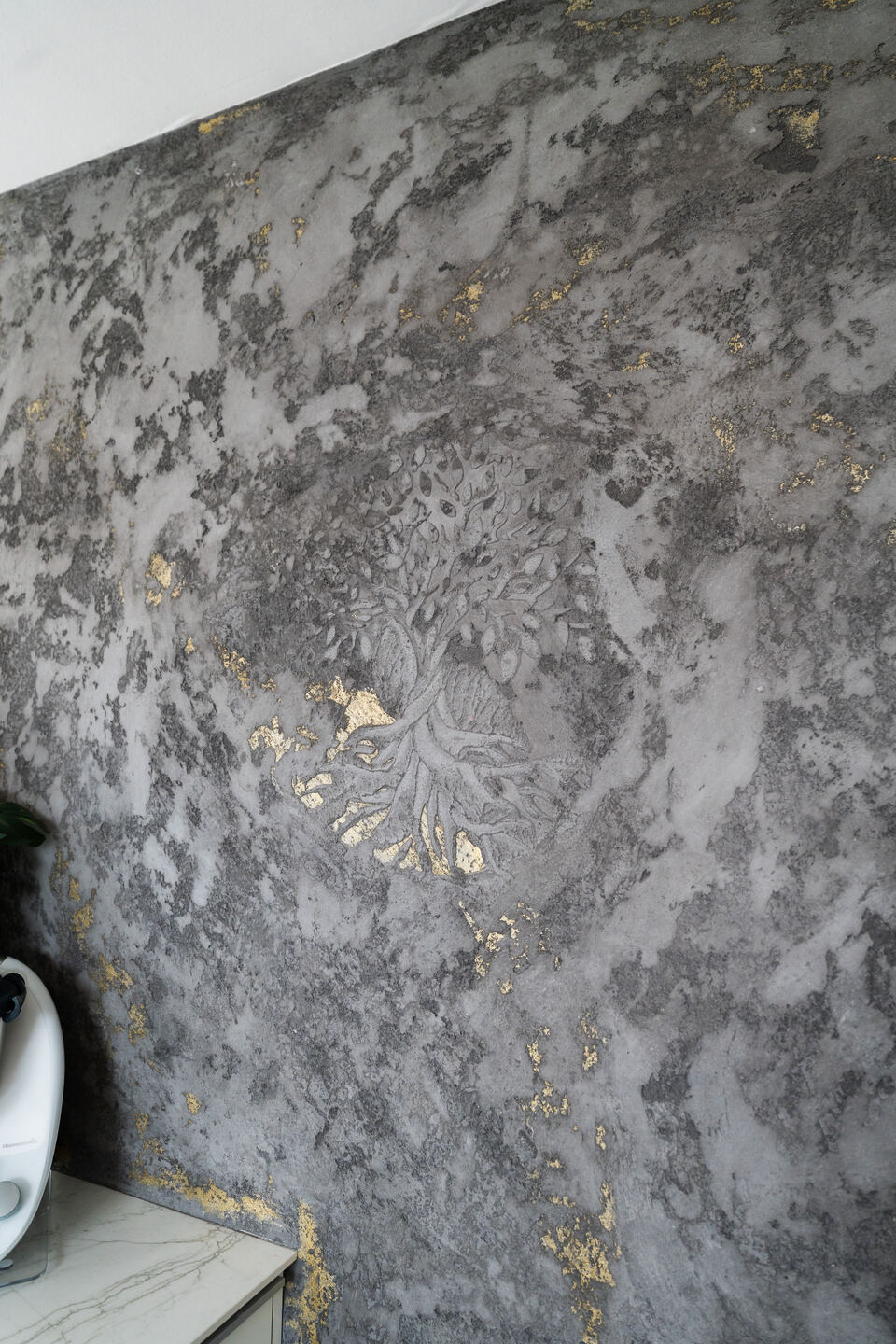Wandgestaltung in Betonoptik mit goldenem Baumornament