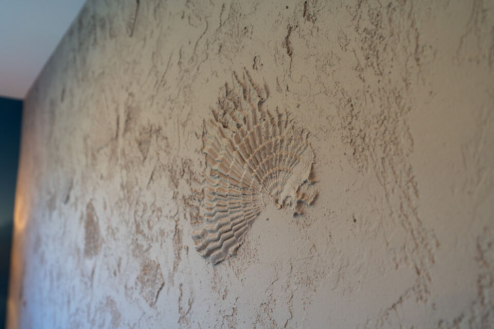 Detailaufnahme einer Wand mit Muschelrelief in Spachteltechnik