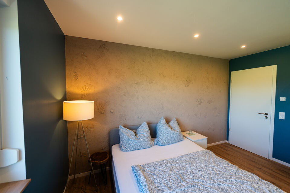 Schlafzimmer mit Akzentwand in Muschellook-Spachteltechnik und Stehleuchte