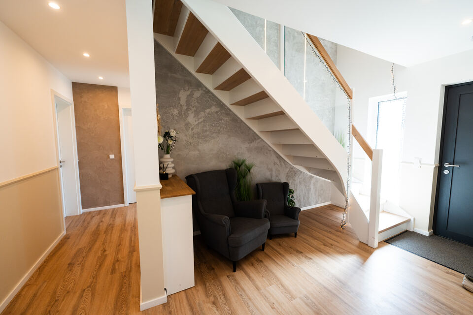 Wohnbereich unter der Treppe mit Wandgestaltung in Betonoptik